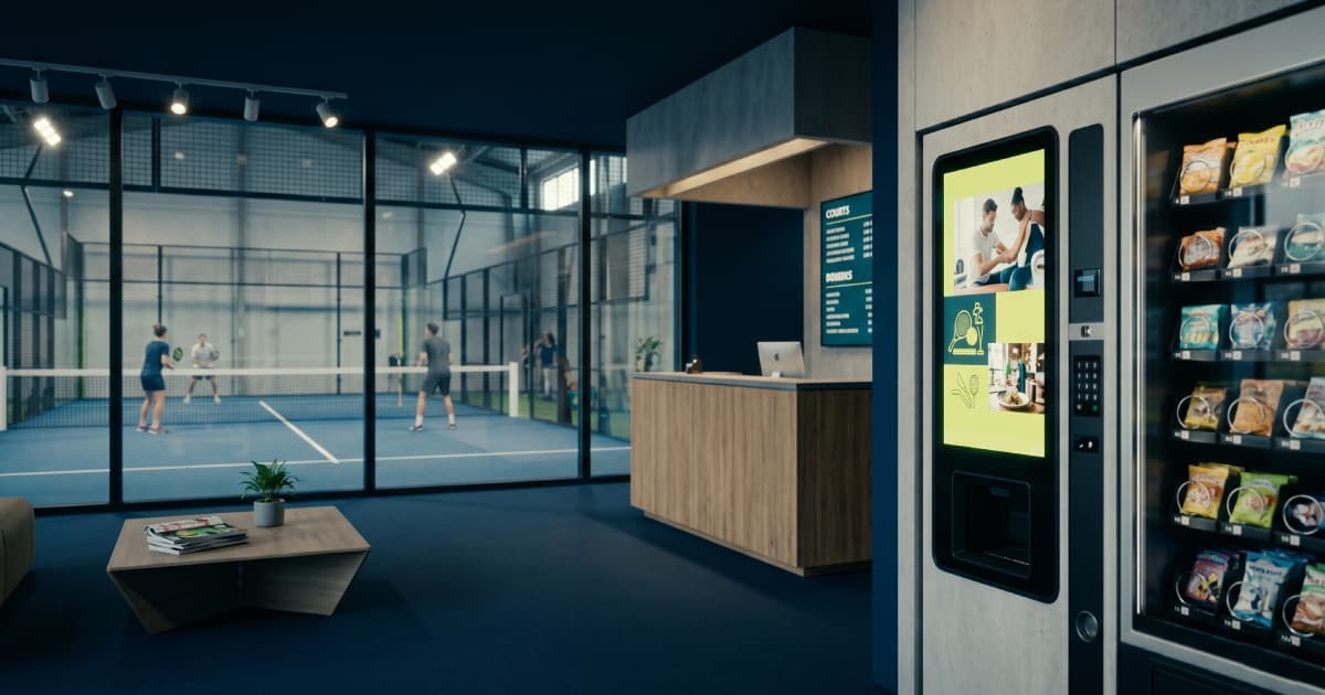 Écran tactile à l'accueil d'un club de padel diffusant la publicité d'un annonceur local entre deux affichages produits — 247kaz